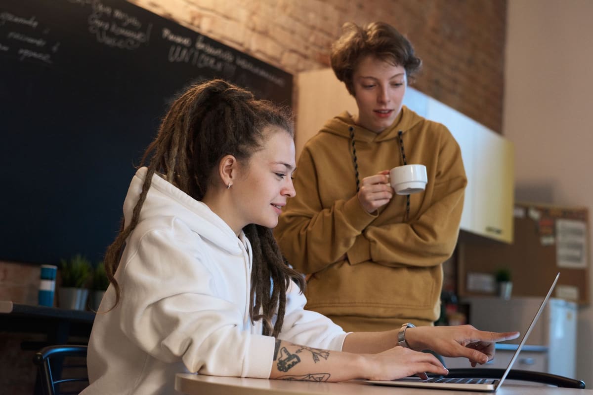 Two colleagues discussing something on a laptop screen