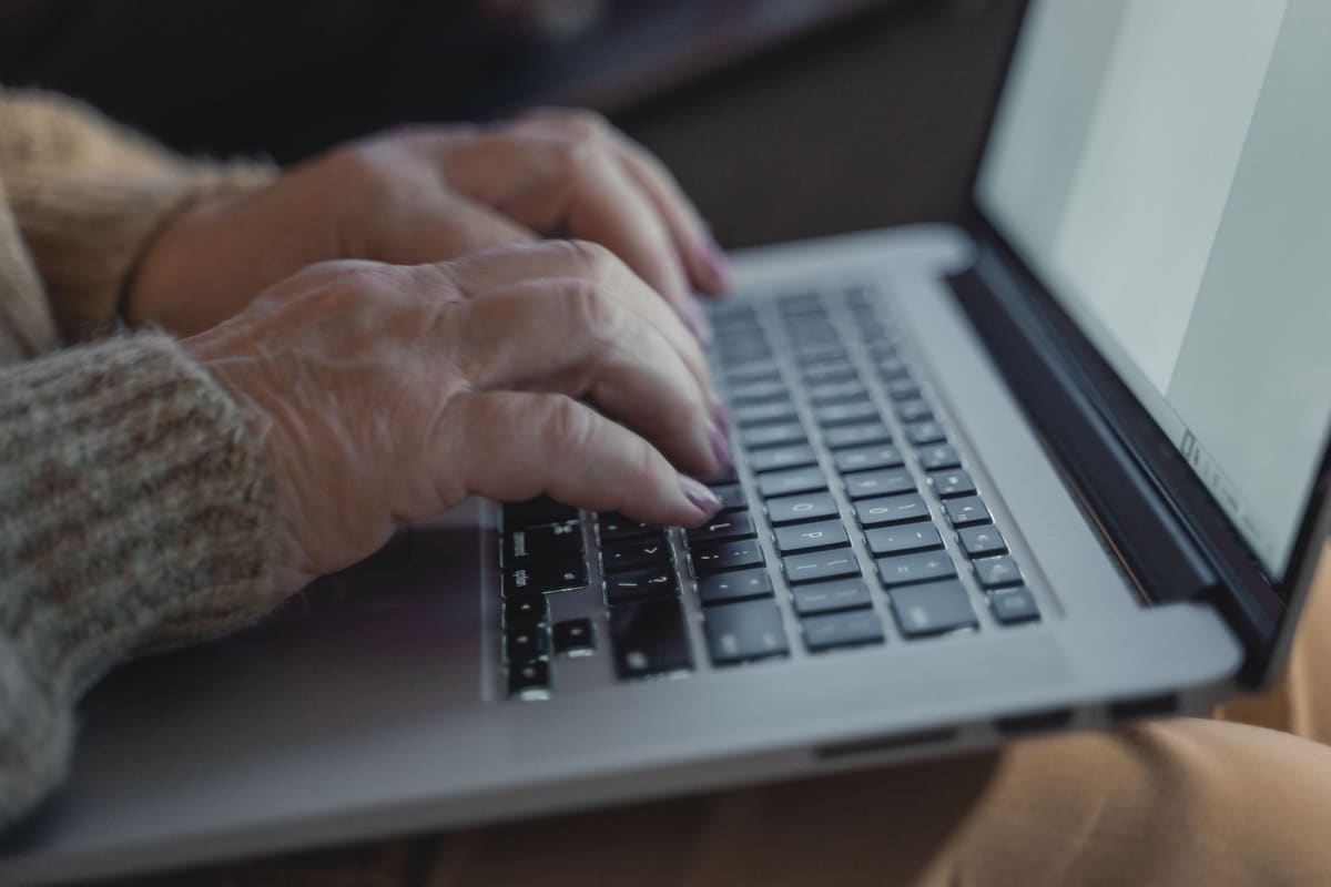 Close-up of hands typing on a laptop keyboard