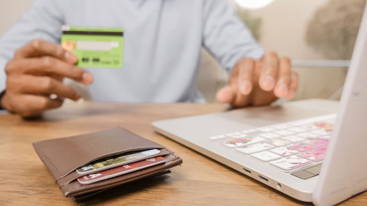 Customer holding a bank card while paying online on a laptop